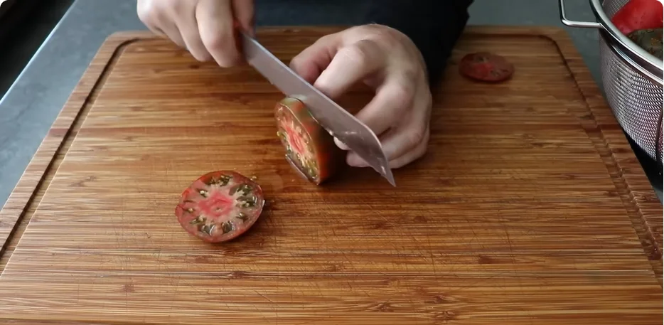 Slicing ripe tomatoes thickly on a wooden board for Southern tomato Frito pie