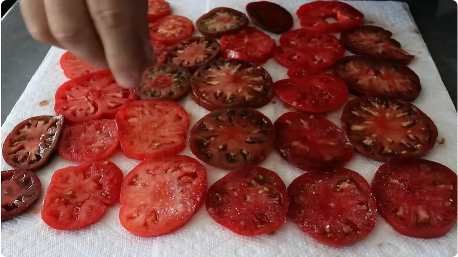 Salted tomato slices resting on paper towels to draw out moisture