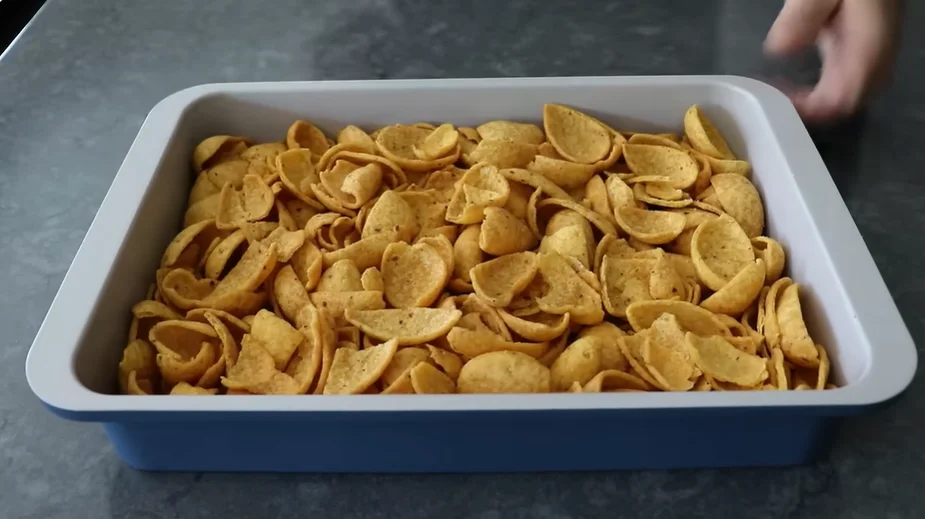 Fritos corn chips layered in a baking dish for tomato Frito pie crust
