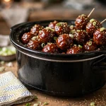 Glossy slow cooker grape jelly meatballs with toothpicks in a crockpot
